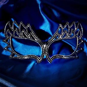 Detail of masquerade mask featuring black rhinestones and butterfly design on blue satin