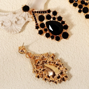 Detail view of vintage gold drop earrings with black crystals and intricate filigree work