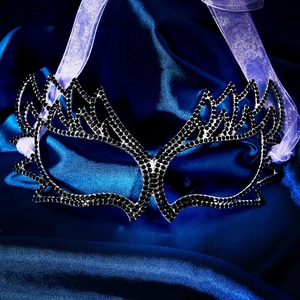 Detail view of a black wing masquerade mask with sparkling rhinestones and purple ribbons
