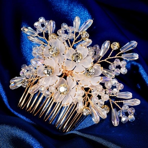 Detail of white frosted flower hair comb with crystal beads and gold wire on blue silk