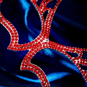 Detailed close-up of sparkling red rhinestones on a silver metal masquerade mask
