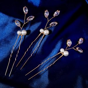 Gros plan de trois épingles à cheveux dorées avec zircons et perles sur soie bleue