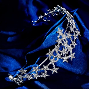 Makroaufnahme von Silber-Haarreif mit Sternen und Strasssteinen auf blauem Seidenstoff