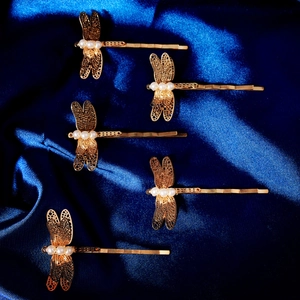 5-teiliges Set goldene Libellen-Haarklammern mit Perlenverzierung auf blauem Seidenstoff