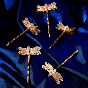 Makroaufnahme der goldenen Libellen-Haarklammer mit Filigranarbeit und weißen Perlen