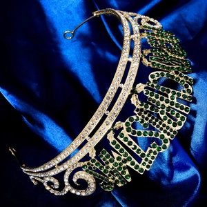 Couronne dorée Miss Universe avec des strass verts et blancs sur un fond en satin bleu