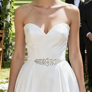 Detailed close-up of handmade bridal belt with sparkling rhinestones on white satin
