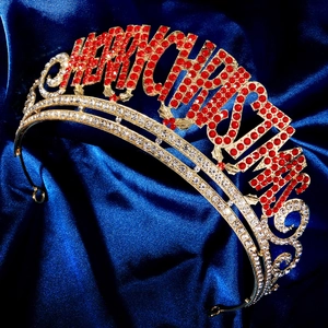 Détail macro de la couronne dorée Merry Christmas avec strass rouges et incolores