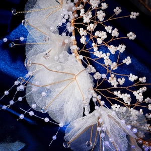 Détail d'un serre-tête de mariée artisanal avec perles blanches et fleurs en dentelle