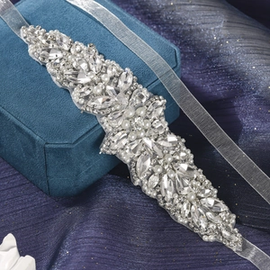 Close-up of handmade bridal belt with marquise crystals and pearls on blue velvet background