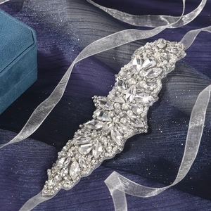 Exquisite rhinestone bridal belt with pearls and crystals on blue tulle background