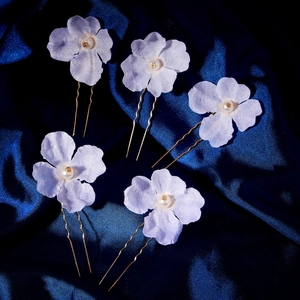 Detail of 5-piece lavender floral hair pins with white pearls on blue silk background