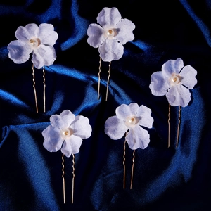 Set of five elegant lilac fabric flower hair pins with pearls on silk background