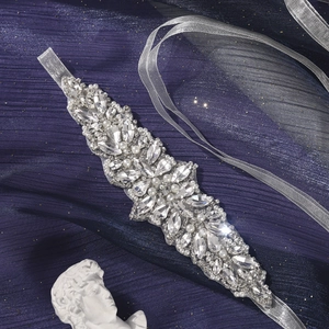 Macro shot of silver bridal belt with marquise rhinestones and white pearls on purple silk