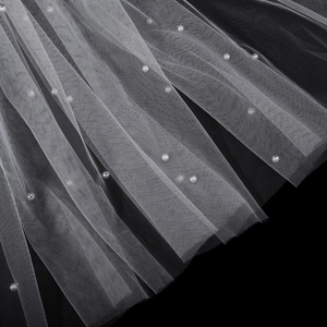 Vista macro dettagliata del velo da sposa in tulle bianco con perle fissate a mano su rete