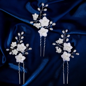 Macro detail of three handmade white resin flower hair pins with pearls and silver U-shaped forks