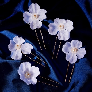 Detailed macro view of five light blue floral U-shaped hair pins with pearls and gold pins
