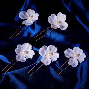Detailed close-up of five handmade bridal flower hair pins with white pearls and gold U-shaped clips