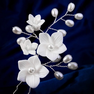 Detailed close-up of white resin flower hair pins with pearls on a dark velvet background