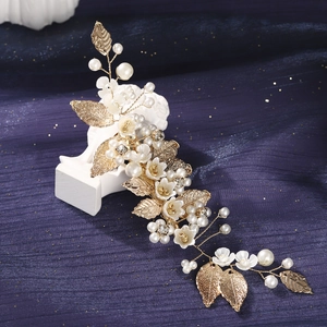 Detailed view of handmade bridal hairpiece with white resin flowers and gold leaves