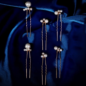 Nahaufnahme von 6 goldenen Braut-Haarnadeln mit Perlen und Strass auf blauem Seidenstoff