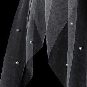 Close-up of white mesh veil with elegant pearls and fine texture on a dark background