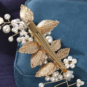 Exquisite gold leaf and pearl bridal hair clip accessory on a blue velvet jewelry box