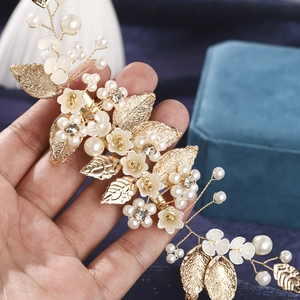 Detail of handmade bridal hair comb with gold leaves, white flowers, and pearls
