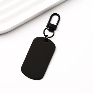 Detail of matte black dog tag keychain with spring gate hook on a minimalist white surface