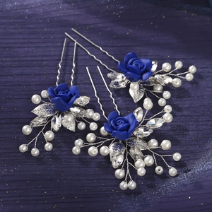 Detailed close-up of handmade bridal hair pins with blue roses and white pearls