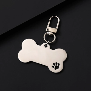 Close-up of bone-shaped stainless steel dog tag with hollow paw print and lobster clasp