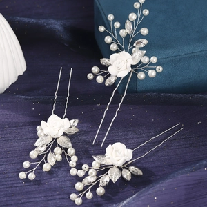 Detail showing white handmade clay flower hair pins with pearls and silver leaves set