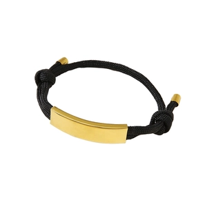 Verstellbares schwarzes Webarmband mit polierter goldener Metallplatte auf weißem Hintergrund