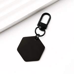 Detailed macro view of a matte black hexagonal metal tag with a lobster clasp fastener