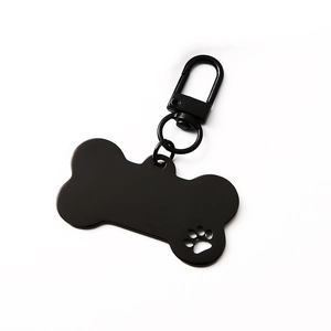 Bone-shaped black metal pet ID tag with hollow paw print and lobster clasp on white background