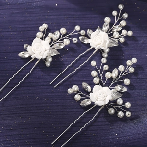 Close-up of white resin rose hair pins with silver leaves, pearls and rhinestones set