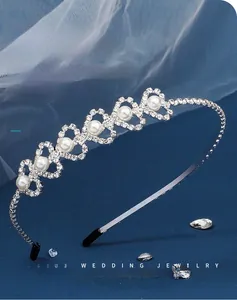 Detail van een zilveren bruidshaarband met holle hartpatronen, parels en strass-stenen