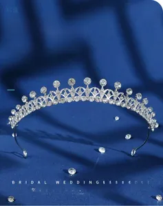 Detail view of silver alloy bridal crown with clear rhinestones on blue silk background