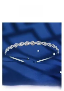 Detailed close-up of a silver tiara headband with teardrop rhinestones on blue silk