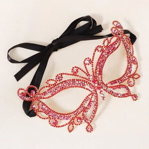 Detailed close-up of a butterfly-shaped masquerade mask with vibrant red rhinestones