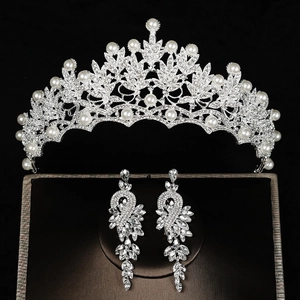 Detailopname van bruidskroon en lange oorbellen met witte parels en heldere strass