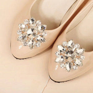 Macro shot of sparkling crystal flower clips on beige patent leather bridal high heels