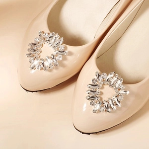 Close-up of sparkling crystal and rhinestone buckle on beige patent leather bridal shoes