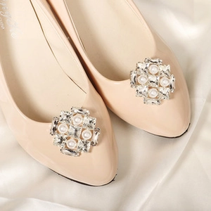 Detail shot of the rhinestone and pearl buckle on the apricot bridal flat shoe with a silk backdrop