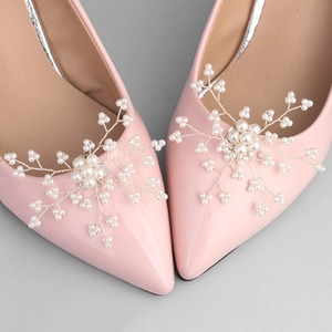 Detailed close-up of pearl snowflake shoe clips on elegant pink high heels
