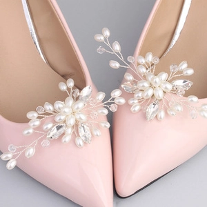 Close-up of handmade bridal shoe clips with pearls and crystals on pink high heels
