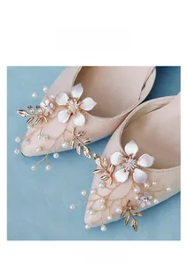 Detailed close-up of bridal shoe clips featuring handmade pearls and floral crystal leaves
