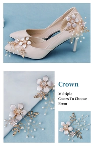 Close-up of handmade white flower shoe clips with pearls and gold leaves for bridal heels