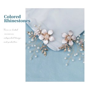 Close-up of handmade white flower and gold leaf bridal shoe clips with faux pearls