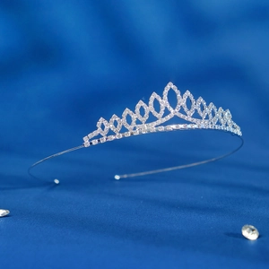 Detail of silver sparkling crystal tiara for kids with rhinestones on blue silk background